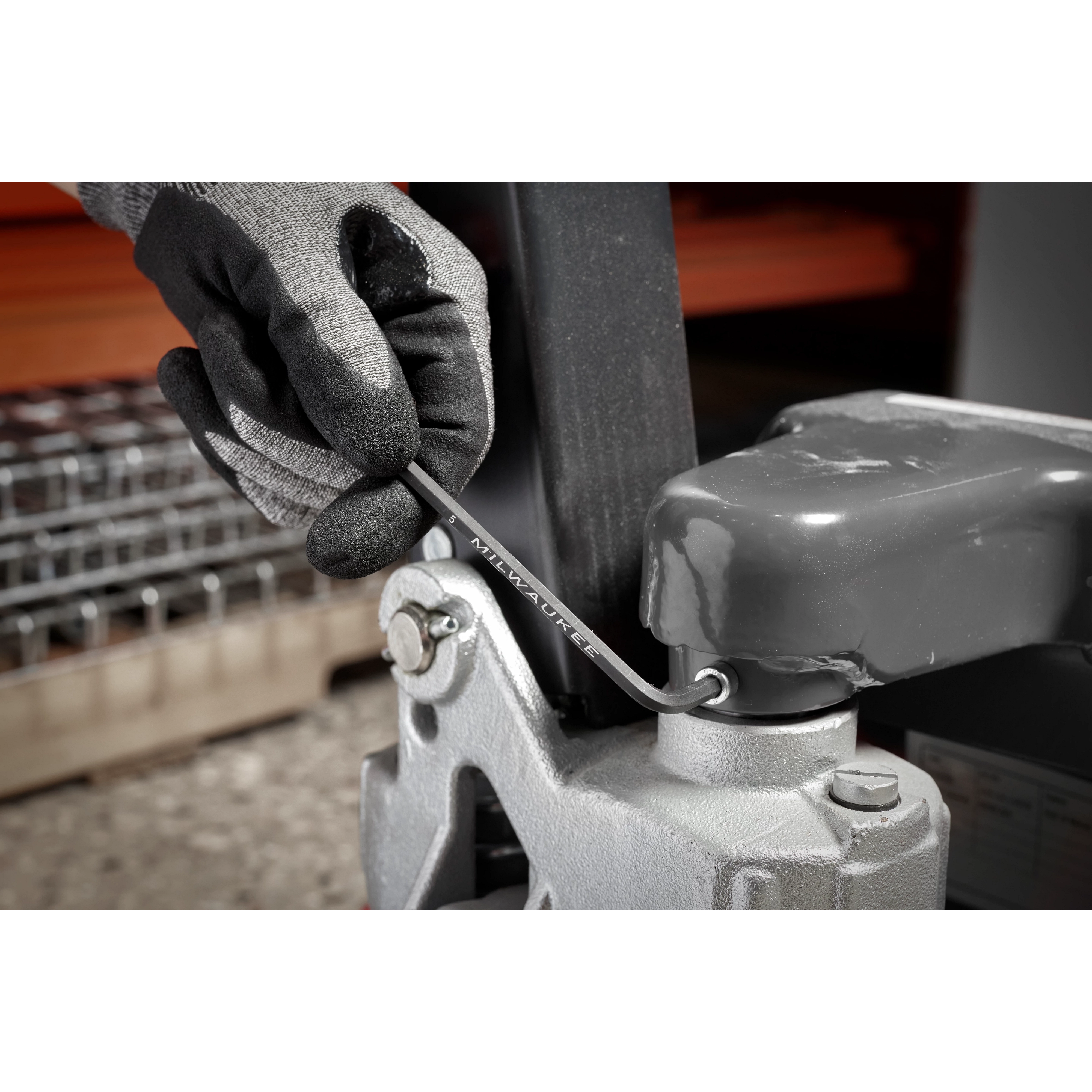 A gloved hand uses an L-key from the 9-Key Ball End L-Key Set - Metric to tighten a bolt on industrial equipment.