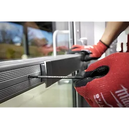 A person wearing red gloves uses a 9-Key Ball End L-Key Set - Metric to adjust a metal door frame with a hex key.